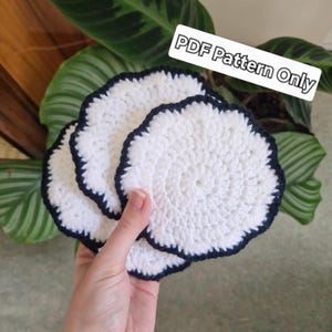 May include: Three white crocheted coasters with black trim. The coasters are stacked on top of each other. The text "PDF Pattern Only" is visible in the image.
