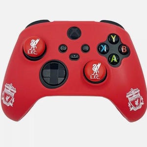 May include: Red Xbox controller with Liverpool Football Club branding. The controller has black buttons and accents, with the team's emblem on the thumbsticks and sides. The controller is a bright red colour.