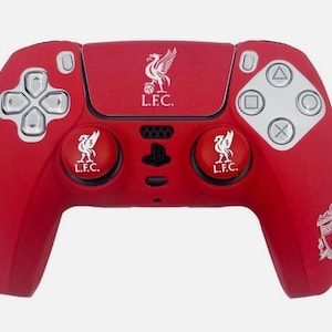 May include: Red PlayStation 5 controller with the Liverpool Football Club emblem. The controller has silver buttons and a directional pad. The Liverpool crest is displayed on the centre and the two circular buttons. The controller has the letters "L.F.C." on it.