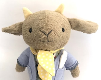 May include: A plush brown goat wearing a blue jacket, a yellow polka dot scarf, and a green and white floral dress.