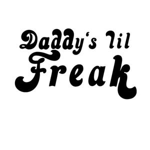 May include: Black and white graphic text that reads "Daddy's lil Freak" in a retro font style.