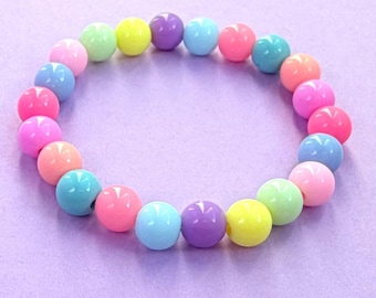 May include: A circular bracelet composed of smooth, round beads in a variety of pastel and bright colors including pink, yellow, purple, blue, green, and peach. The beads are arranged in a repeating pattern to form a continuous loop of jewelry.