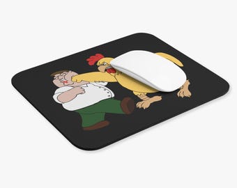 Op de afbeelding: Een rechthoekige zwarte muismat met een grafische illustratie van een gele kip die een man in een wit overhemd en een groene broek slaat. Een witte computermuis rust op het oppervlak van de muismat en bedekt gedeeltelijk de illustratie.