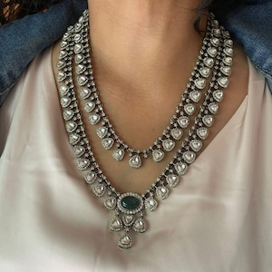 Puede incluir: Un collar de dos capas de plata y verde con un colgante de piedra preciosa verde grande. El collar est&aacute; hecho de peque&ntilde;as piedras en forma de l&aacute;grima.