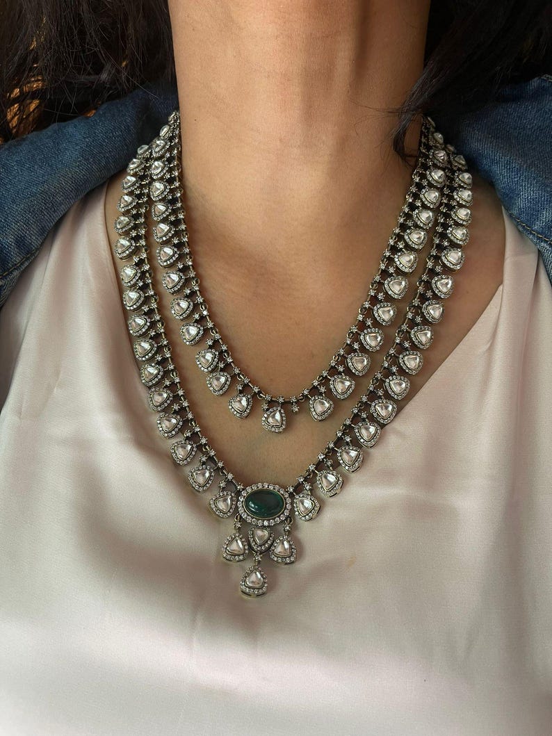 Puede incluir: Un collar de dos capas de plata y verde con un colgante de piedra preciosa verde grande. El collar est&aacute; hecho de peque&ntilde;as piedras en forma de l&aacute;grima.