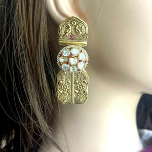 May include: Gold tone earrings with a floral design and white and pink gemstones.