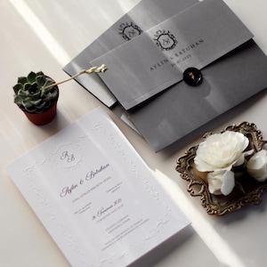 Elegante grijze envelop huwelijksuitnodiging, klassieke witte kaart met reliëf, luxe bruiloft briefpapier met monogram, gepersonaliseerde bruiloft uitnodiging