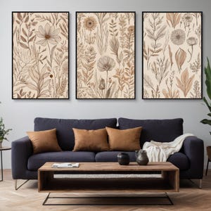 Op de afbeelding: Drie ingelijste prints met een beige achtergrond en bruine lijntekeningen van verschillende bloemen en planten.