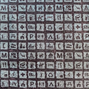 Könnte beinhalten: Ein brauner Stoff mit einem sich wiederholenden Muster aus weißen Symbolen. Die Symbole zeigen verschiedene Outdoor-Aktivitäten wie Camping, Wandern, Angeln und Schwimmen. Die Symbole sind in einem Raster angeordnet.