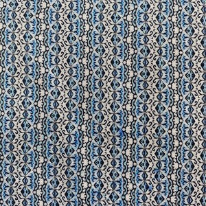 May include: Close-up of a fabric with a repeating pattern. The design features vertical stripes with alternating patterns of diamonds and ornate scrollwork in shades of blue, black, and white. The fabric has a textured appearance.
