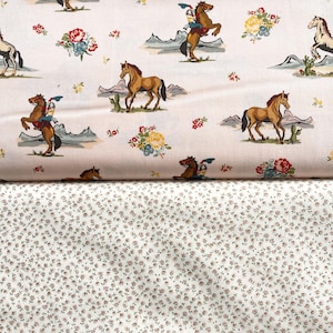 May include: Two fabric patterns. The top fabric has a cream background with a repeating pattern of cowboys on horses, mountains, cacti, and floral bouquets in red, yellow, and blue. The bottom fabric has a white background with a small, repeating floral pattern in red and brown.