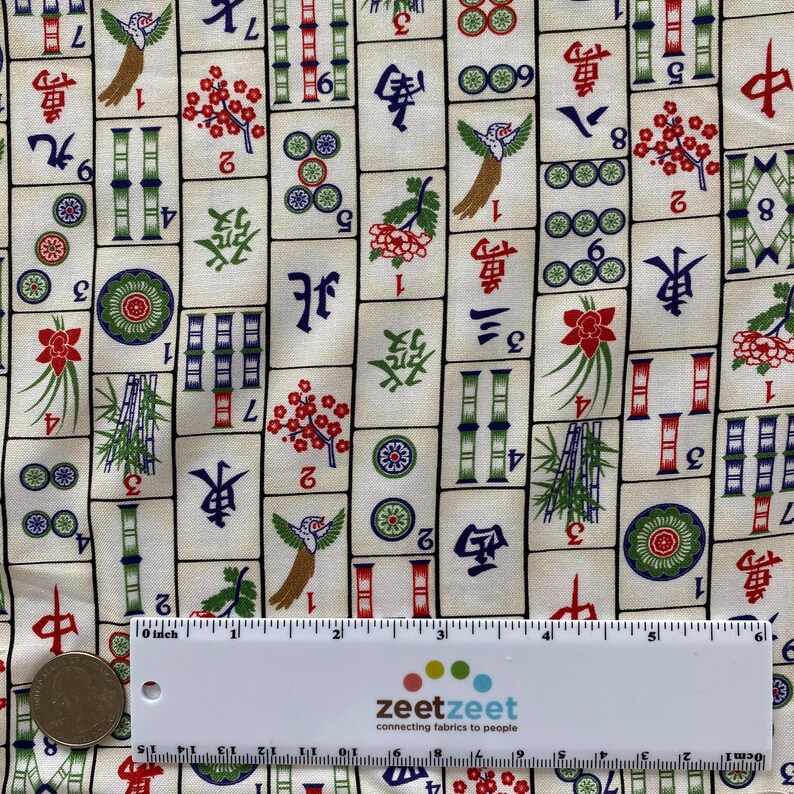 May include: Cream-colored fabric with a repeating pattern of Mahjong tiles. The tiles feature Chinese characters, floral designs, and bird illustrations in red, green, and blue. A ruler shows measurements in inches.