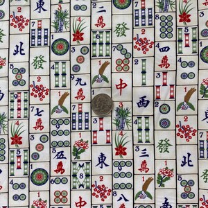 May include: A fabric featuring a repeating pattern of Mahjong tiles. The tiles are white with black, red, green, and blue symbols and characters. The design includes bamboo, flowers, and circles. A quarter is included for scale.