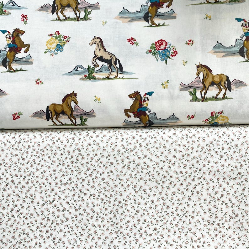 May include: White fabric featuring a repeating design of horses, cowboys, cacti, and floral arrangements in brown, blue, red, and yellow. Beneath is a fabric with a small, repeating floral pattern in white and brown.