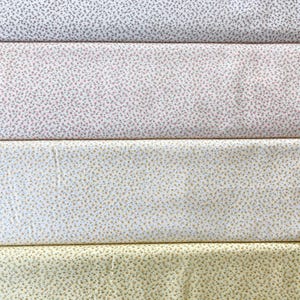 May include: Four fabric swatches with floral patterns. The top swatch is white with small gray flowers. The second swatch is pink with tiny red and green flowers. The third swatch is white with small yellow flowers. The bottom swatch is yellow with small brown flowers.