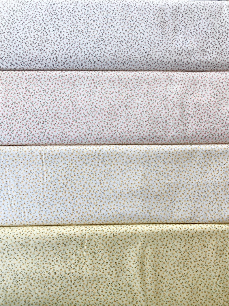 May include: Four fabric swatches with floral patterns. The top swatch is white with small gray flowers. The second swatch is pink with tiny red and green flowers. The third swatch is white with small yellow flowers. The bottom swatch is yellow with small brown flowers.