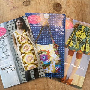 May include: Three sewing patterns featuring a floral design. The patterns are titled "Socialite Dress", "Multi-Tasker Tote", and "Lady Hall Skirt".
