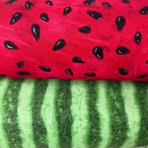 May include: Two pieces of fabric with watermelon prints. The top piece is red with black seeds and the bottom piece is green with black stripes.