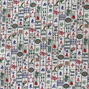 May include: A fabric with a repeating pattern of Mahjong tiles. The tiles are cream-colored with black, red, green, and blue symbols and characters. The design includes flowers, bamboo, and circles.