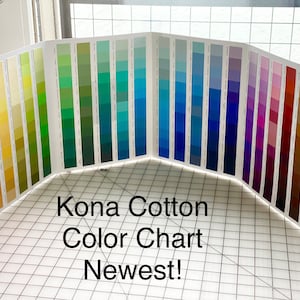May include: A color chart displaying a wide array of Kona Cotton fabric swatches. The chart is fanned out, showcasing a spectrum of colors from pinks and yellows to blues and greens. Text on the chart reads "Kona Cotton Color Chart Newest!"