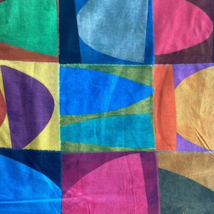 May include: A colorful patchwork textile featuring a grid of squares with abstract shapes. The design incorporates various colors, including green, blue, yellow, purple, pink, and orange. The shapes are primarily curved and geometric, creating a vibrant and artistic pattern.