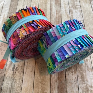 May include: Two rolls of colourful fabric strips, secured with light blue ribbon. The fabric displays a variety of vibrant colours and patterns, including floral and abstract designs. Suitable for quilting or other fabric crafts.