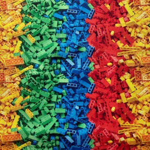 Könnte beinhalten: Nahaufnahme eines bunten Stoffes mit einem Muster aus kleinen Plastikbausteinen. Die Bausteine sind in vertikalen Streifen in Gelb, Grün, Blau und Rot angeordnet.