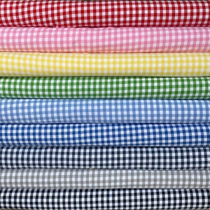 May include: A stack of colourful gingham fabric in various colours, including red, pink, yellow, green, blue, navy, black, and grey. The fabric is folded and stacked, showing the gingham pattern.