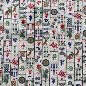 May include: Off-white fabric with a repeating pattern of colorful Mahjong tiles. The tiles feature Chinese characters, bamboo, flowers, and circles in red, green, and blue. A decorative textile.