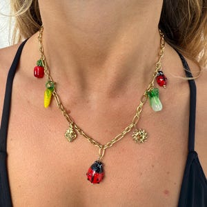 Gold necklace with multiple charms, red ladybug, sun, chili pepper and strawberry, personalized jewelry creation in stainless steel