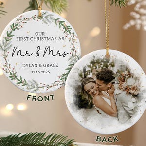 May include: A round, white Christmas ornament with a gold string. The front features text: "OUR FIRST CHRISTMAS AS Mr & Mrs" with names and a date. The back displays a photo of a couple. Green and red accents surround the text.