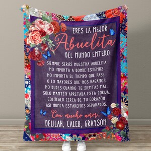 May include: A purple and red floral patterned blanket with a message in Spanish that reads "Eres la mejor Abuelita del mundo entero. Siempre ser&aacute;s nuestra abuelita. No importa a donde estemos. No importa el tiempo que pase. O lo mayores que nos hagamos. No dudes cuando te sientas mal. Solo mant&eacute;n apretada esta cobija. Col&oacute;calo cerca de tu coraz&oacute;n. As&iacute; nunca estaremos separados. Con mucho amor, Delilah, Caleb, Grayson."