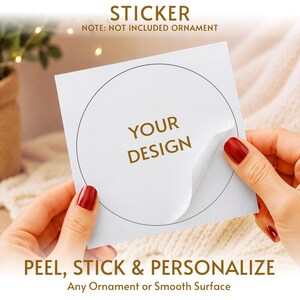 May include: A square white sticker sheet featuring a circular die-cut outline and the gold text YOUR DESIGN in the centre. The sticker is partially peeled back from the backing paper. Text on the image reads STICKER, NOTE: NOT INCLUDED ORNAMENT, PEEL, STICK & PERSONALIZE, Any Ornament or Smooth Surface.