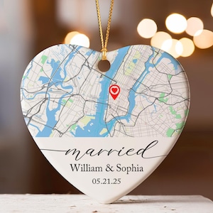 May include: Heart-shaped ornament featuring a map of New York City with a red marker. The ornament has the word "married", names "William & Sophia", and the date "05.21.25" in black script. A gold string is attached for hanging.