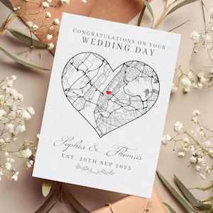 Puede incluir: Una tarjeta de boda blanca con un mapa en forma de corazón de una ciudad, un corazón rojo que marca una ubicación y el texto "Felicidades en tu día de boda". Los nombres "Sophia & Thomas" y la fecha "EST. 20th SEP 2025" también están impresos.