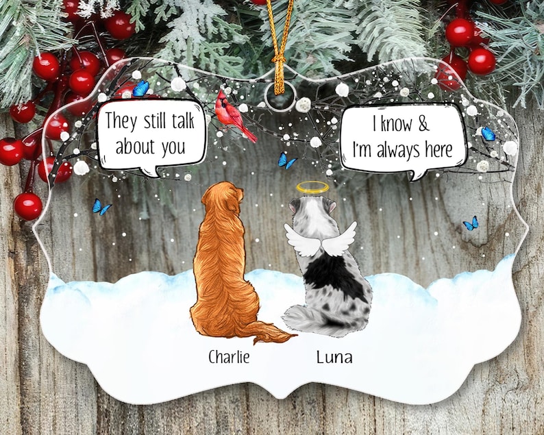 May include: A clear, scalloped-edge ornament featuring a golden retriever named Charlie and a spotted dog named Luna with angel wings and a halo. Speech bubbles read, They still talk about you and I know & I'm always here, amidst snow and blue butterflies.