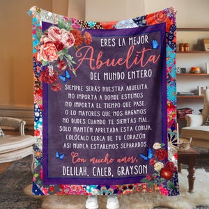 May include: A purple and blue blanket with a floral design and a message in Spanish that reads "Eres la mejor Abuelita del mundo entero. Siempre ser&aacute;s nuestra abuelita. No importa a donde estemos. No importa el tiempo que pase. O lo mayores que nos hagamos. No dudes cuando te sientas mal. Solo mant&eacute;n apretada esta cobija. Col&oacute;calo cerca de tu coraz&oacute;n. As&iacute; nunca estaremos separados. Con mucho amor, Delilah, Caleb, Grayson."