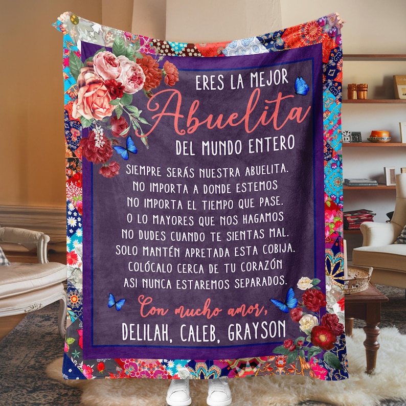 May include: A purple and blue blanket with a floral design and a message in Spanish that reads "Eres la mejor Abuelita del mundo entero. Siempre ser&aacute;s nuestra abuelita. No importa a donde estemos. No importa el tiempo que pase. O lo mayores que nos hagamos. No dudes cuando te sientas mal. Solo mant&eacute;n apretada esta cobija. Col&oacute;calo cerca de tu coraz&oacute;n. As&iacute; nunca estaremos separados. Con mucho amor, Delilah, Caleb, Grayson."