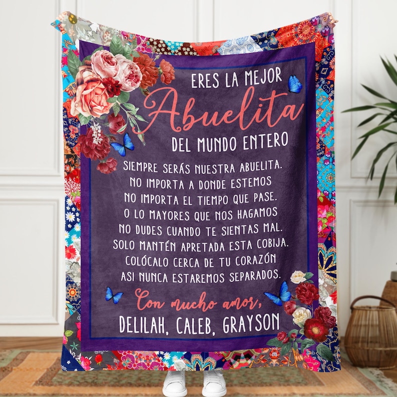 May include: A purple and blue blanket with a floral design and a message in Spanish that reads "Eres la mejor Abuelita del mundo entero. Siempre ser&aacute;s nuestra abuelita. No importa a donde estemos. No importa el tiempo que pase. O lo mayores que nos hagamos. No dudes cuando te sientas mal. Solo mant&eacute;n apretada esta cobija. Col&oacute;calo cerca de tu coraz&oacute;n. As&iacute; nunca estaremos separados. Con mucho amor, Delilah, Caleb, Grayson."