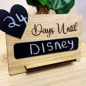 May include: A wooden countdown sign with a chalkboard heart that says "24" and a chalkboard rectangle that says "Disney". The sign also has the text "Days Until" engraved on it.