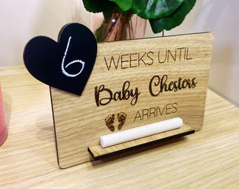 May include: Wooden countdown sign with a black heart chalkboard that says "6" and the text "Weeks until Baby Chesters arrives".