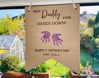 May include: Wooden sign with the text "BEST Daddy EVER HANDS DOWN!" and purple handprints. Below the text is "HAPPY 1st FATHER'S DAY LOVE. Charlie xxx".