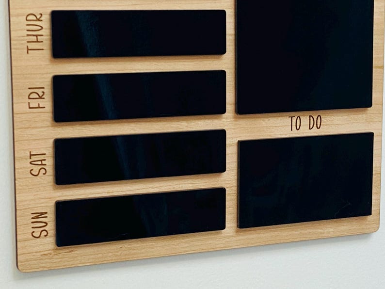 May include: A wooden weekly planner with black chalkboard-style sections for each day of the week, Sunday through Thursday, and a larger section labeled "To Do".