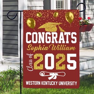 May include: A maroon graduation yard sign with gold glitter accents. The sign says "Congrats Sophia William Class of 2025 Western Kentucky University".