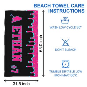 May include: Black beach towel with pink and blue dripping icing and sprinkles. The towel has the name "AETHAN #7" in pink letters. The towel is 31.5 inches wide and 63 inches long. Care instructions include washing on a low cycle at 30 degrees, not bleaching, and tumble drying on low. Ironing is allowed at a maximum temperature of 100 degrees Celsius.
