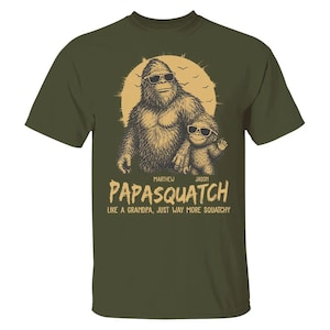 May include: Olive green t-shirt with a Bigfoot graphic wearing sunglasses, alongside a smaller Bigfoot. The text says "Papasquatch" and "Like a grandpa, just way more squatchy."