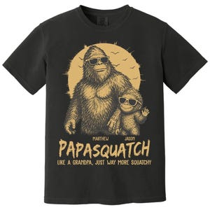 May include: Black t-shirt with a gold illustration of a Bigfoot and a smaller Bigfoot, both wearing sunglasses. The text says "PAPASQUATCH" and "LIKE A GRANDPA, JUST WAY MORE SQUATCHY".