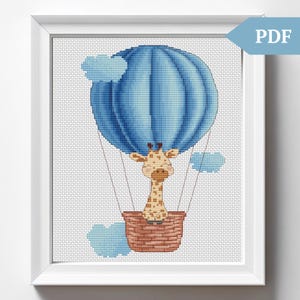 May include: A cross-stitch pattern featuring a cute giraffe riding in a blue hot air balloon with clouds in the background.