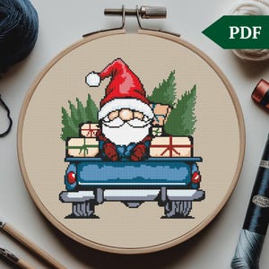 May include: A cross-stitch pattern featuring a Santa Claus character driving a blue pickup truck with Christmas trees and presents in the back.