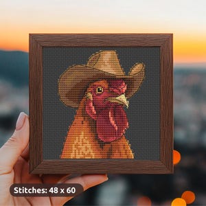 May include: A framed cross-stitch of a rooster wearing a cowboy hat. The rooster is rendered in shades of orange, red, and brown against a dark gray background. The frame is a dark brown color. The text "Stitches: 48 x 60" is at the bottom.